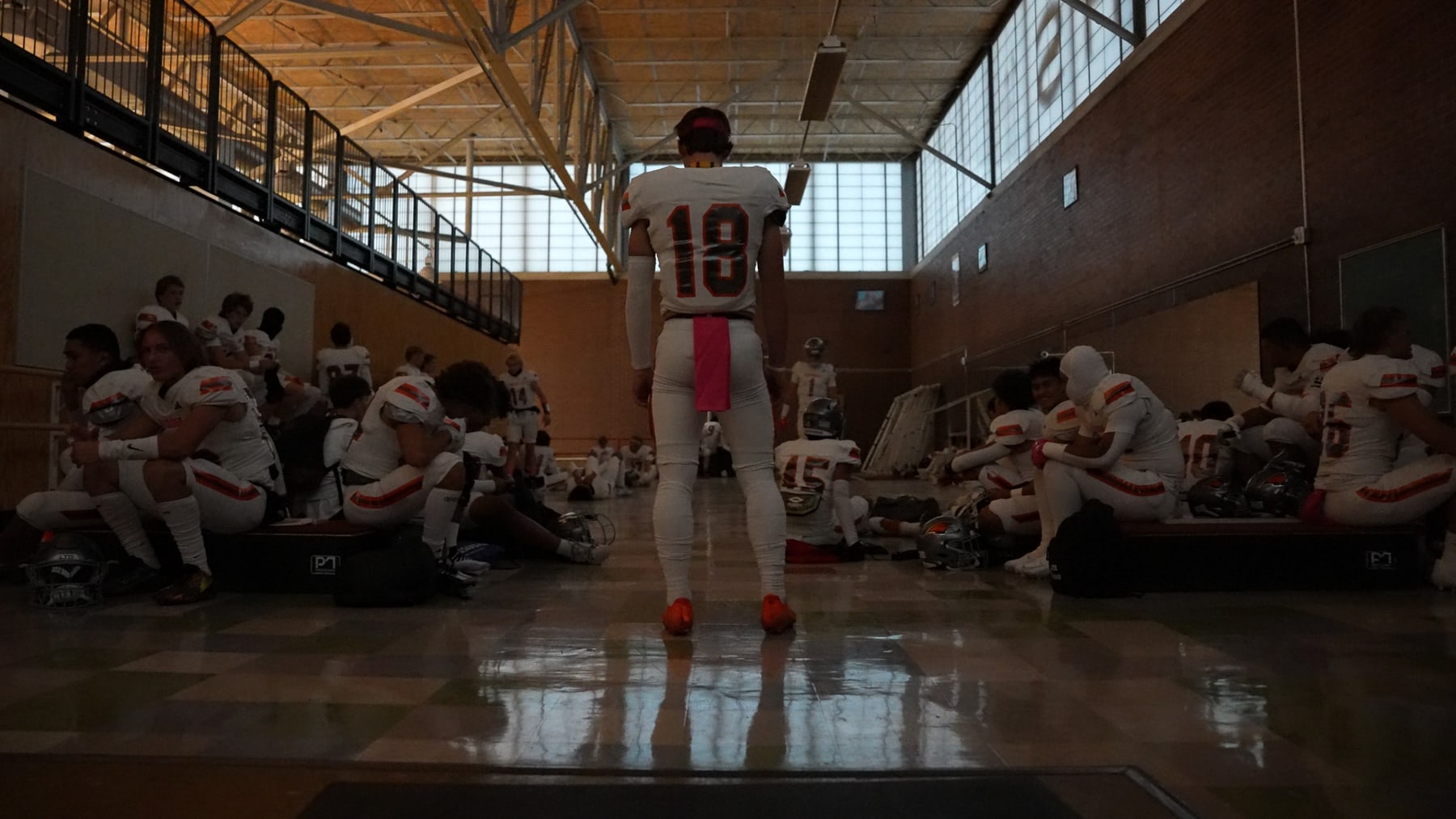 Porter Logan standing in a locker room with teammates seated around him
